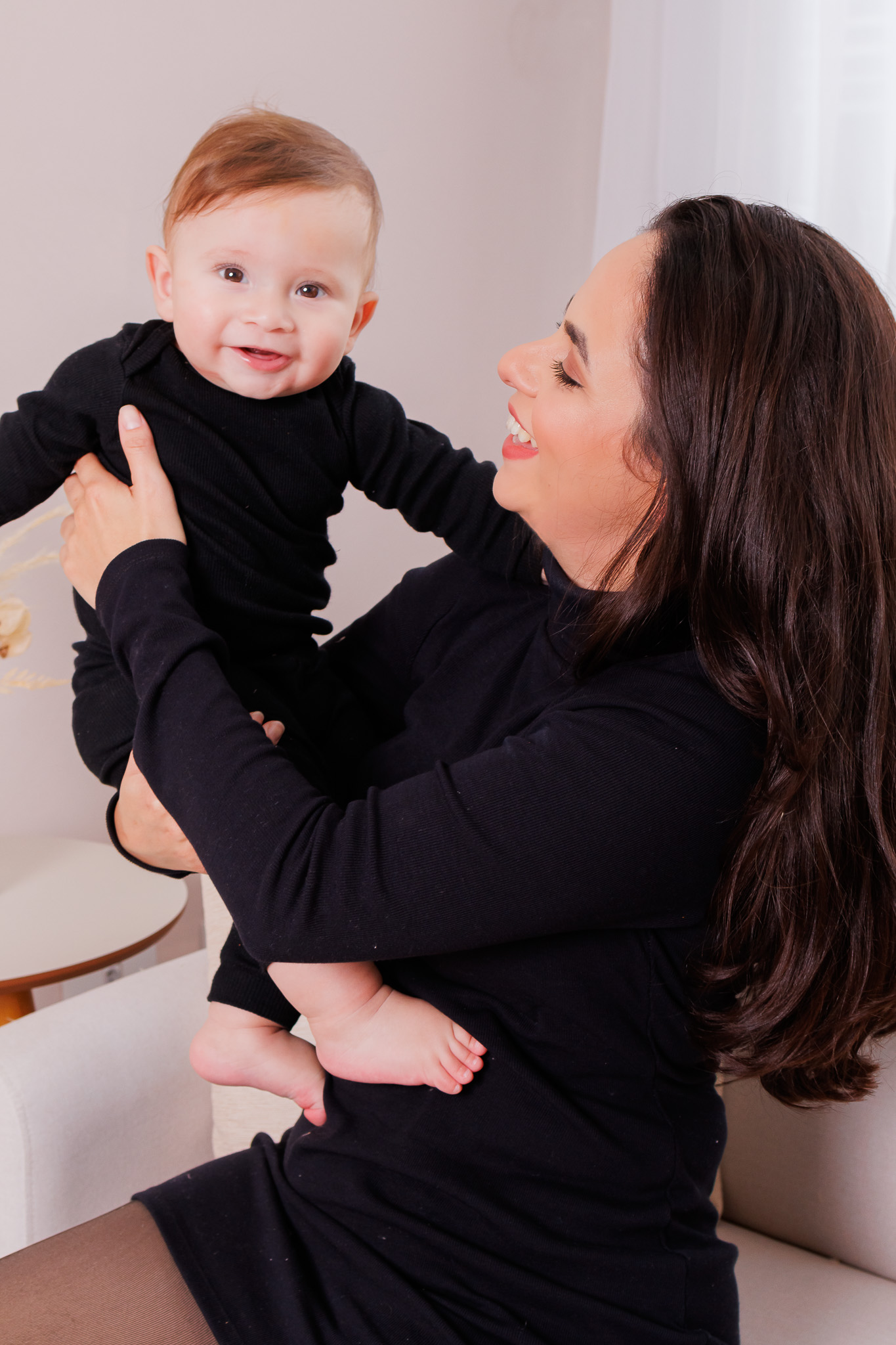 Todos pela acessibilidade: Um retrato íntimo focado nos detalhes, como as mãos entrelaçadas da mãe e da filha. A luz de estúdio, cuidadosamente ajustada, ilumina suavemente os detalhes, revelando a profundidade do vínculo entre elas. A fotógrafa usou sua habilidade para criar uma sensação de calma e ternura na imagem.